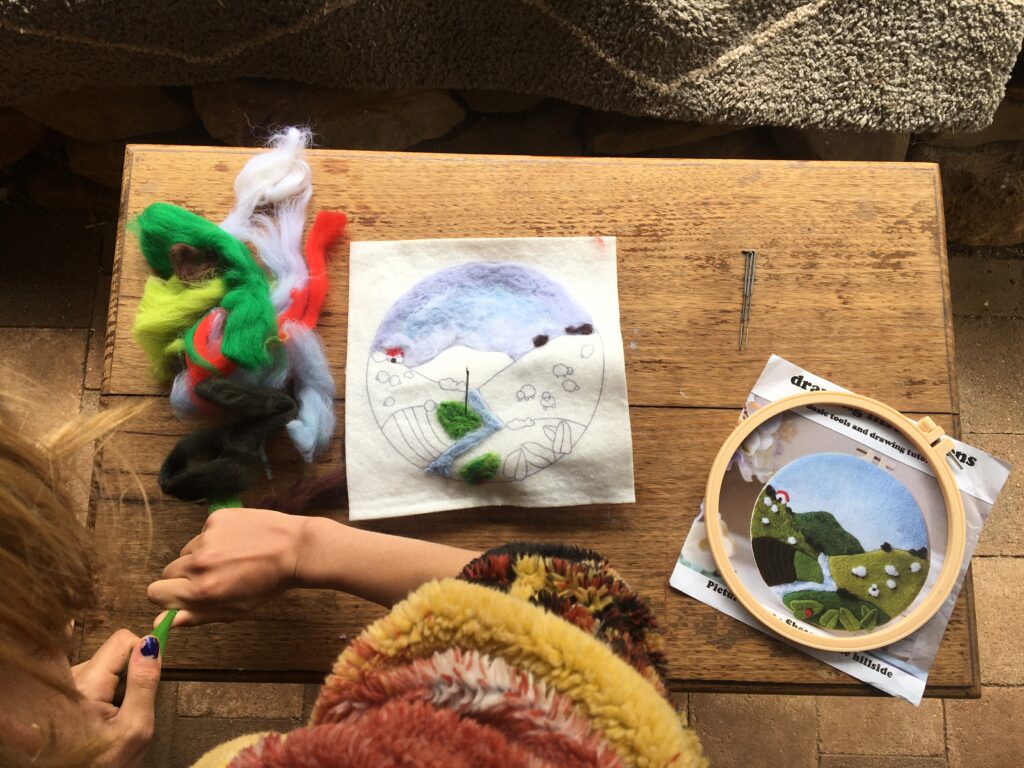 Hands working on a small nature-inspired felting project